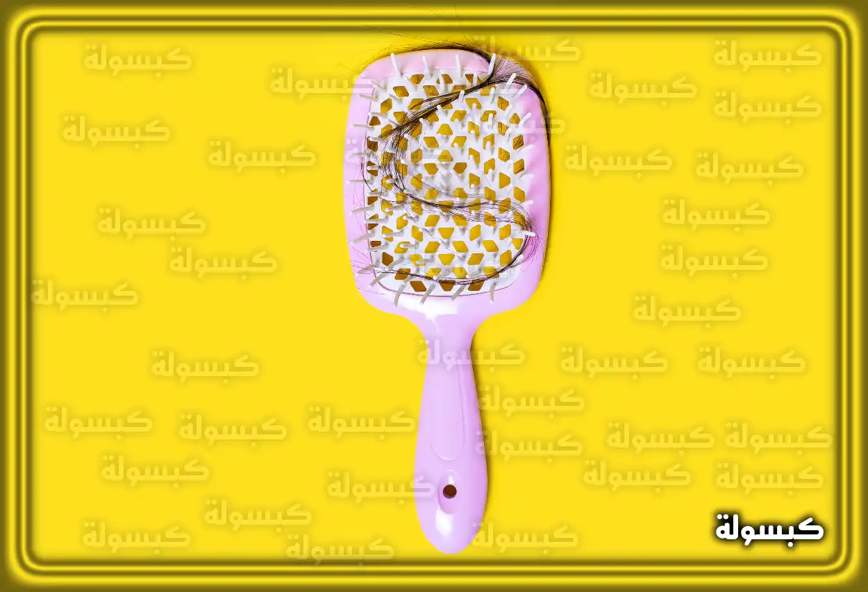 امرأة تمشط شعرها أمام المرآة وينظر إلى الشعر المتساقط في المشط