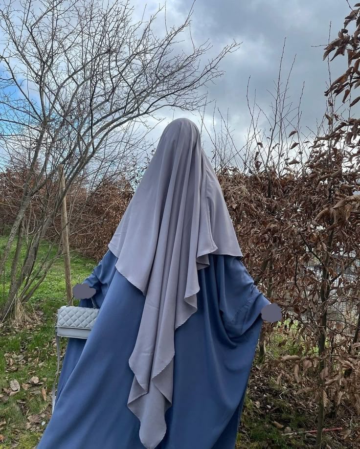 فتاة ترتدي خمارًا أبيض اللون وتنظر إلى الكاميرا